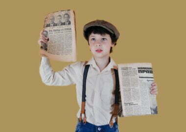 stylish boy showing aged newspapers against yellow background