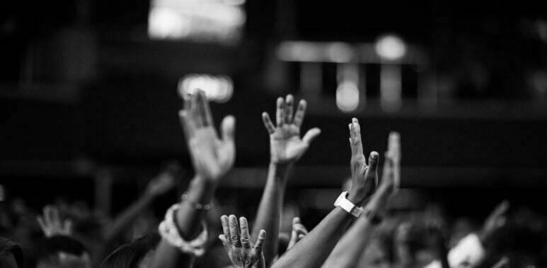 Grayscale photography of people raising hands