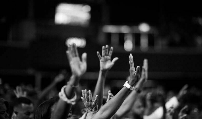 Grayscale photography of people raising hands